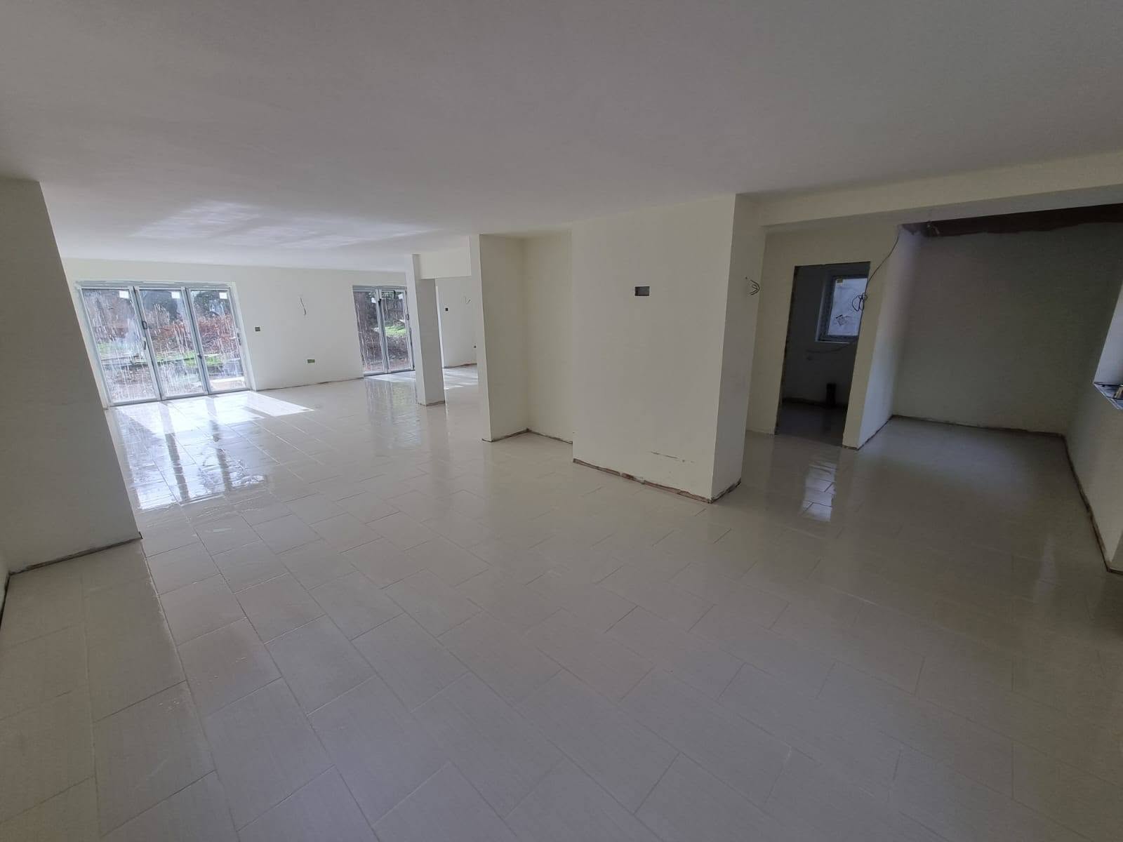 Large open-plan room with newly laid white floor tiles