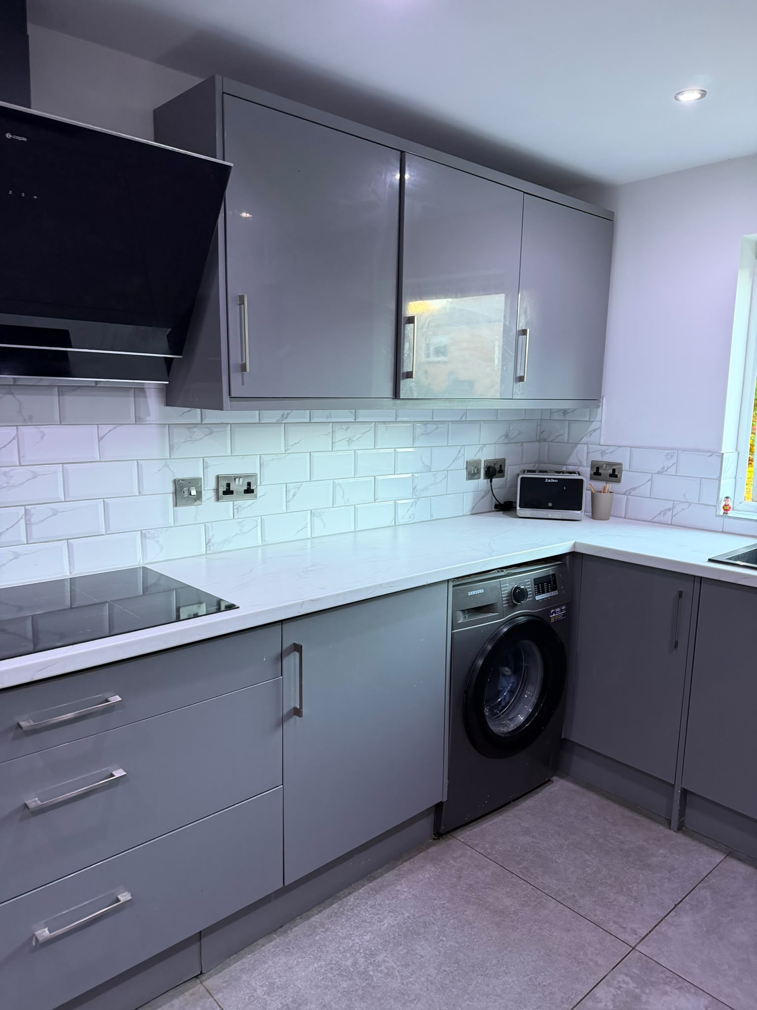 Kitchen with grey units and a white metro-tile splashback