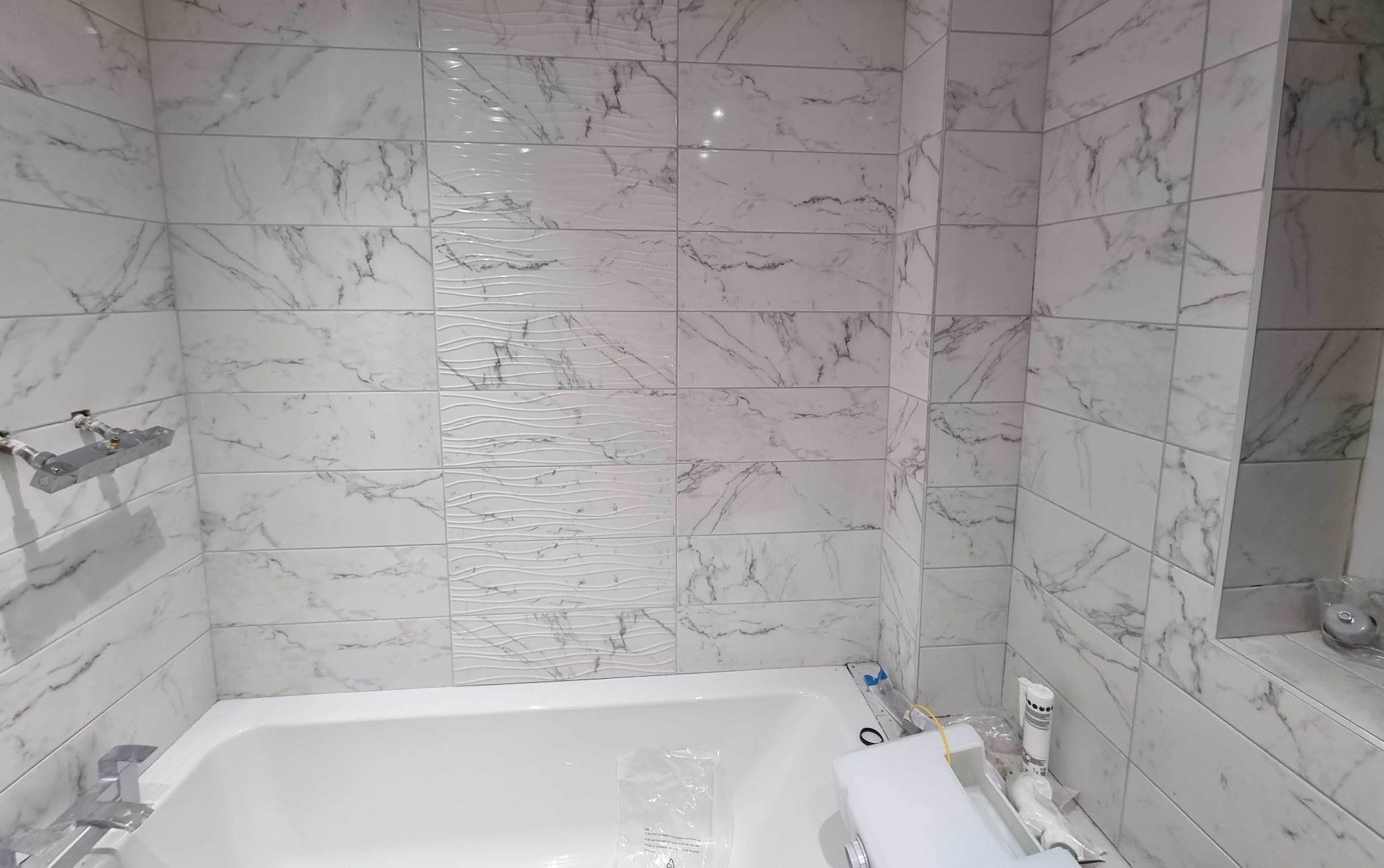 Bath wall finished in white marble-effect tiles