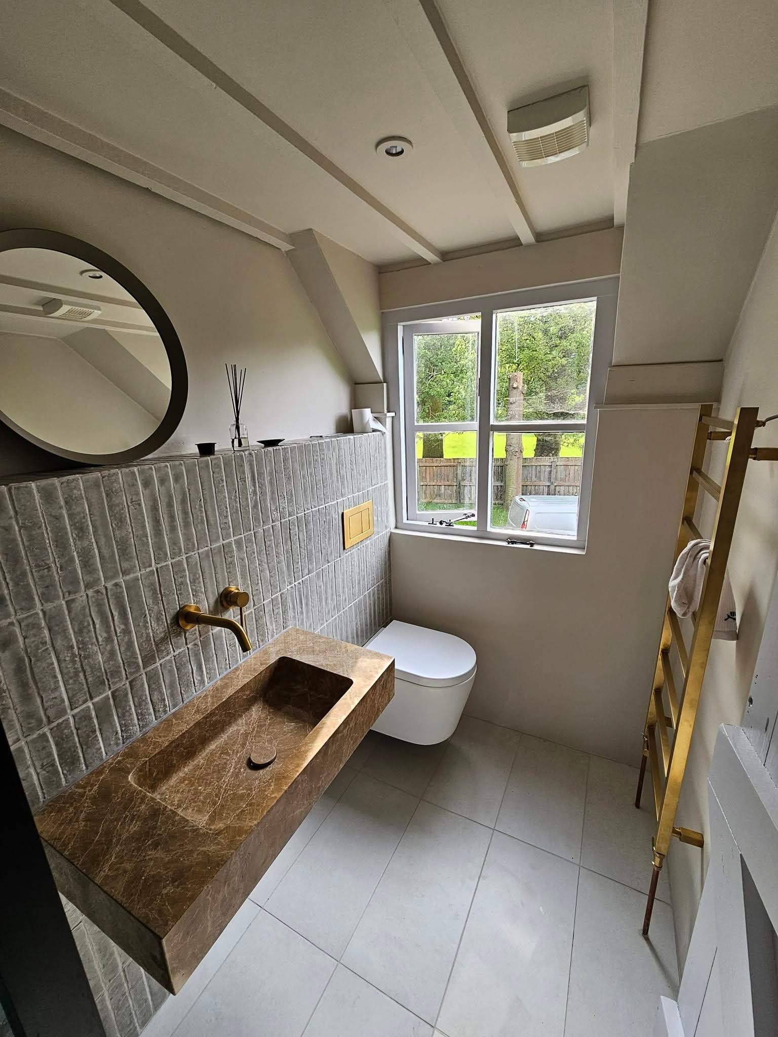 Cloakroom with sage vertical wall tiles, a stone basin and a brass towel ladder