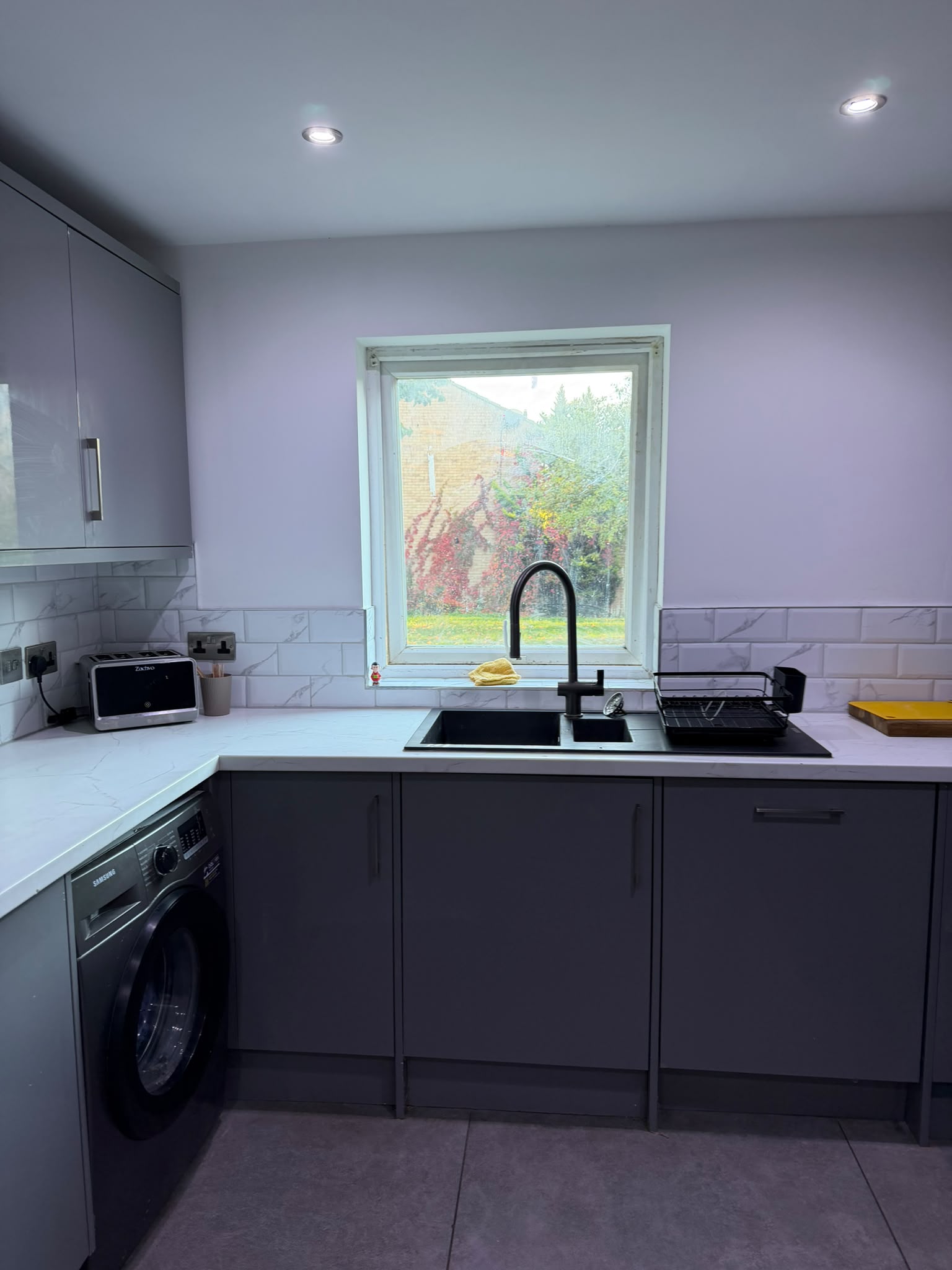 Kitchen sink run beneath a window, with metro tiles above the worktop