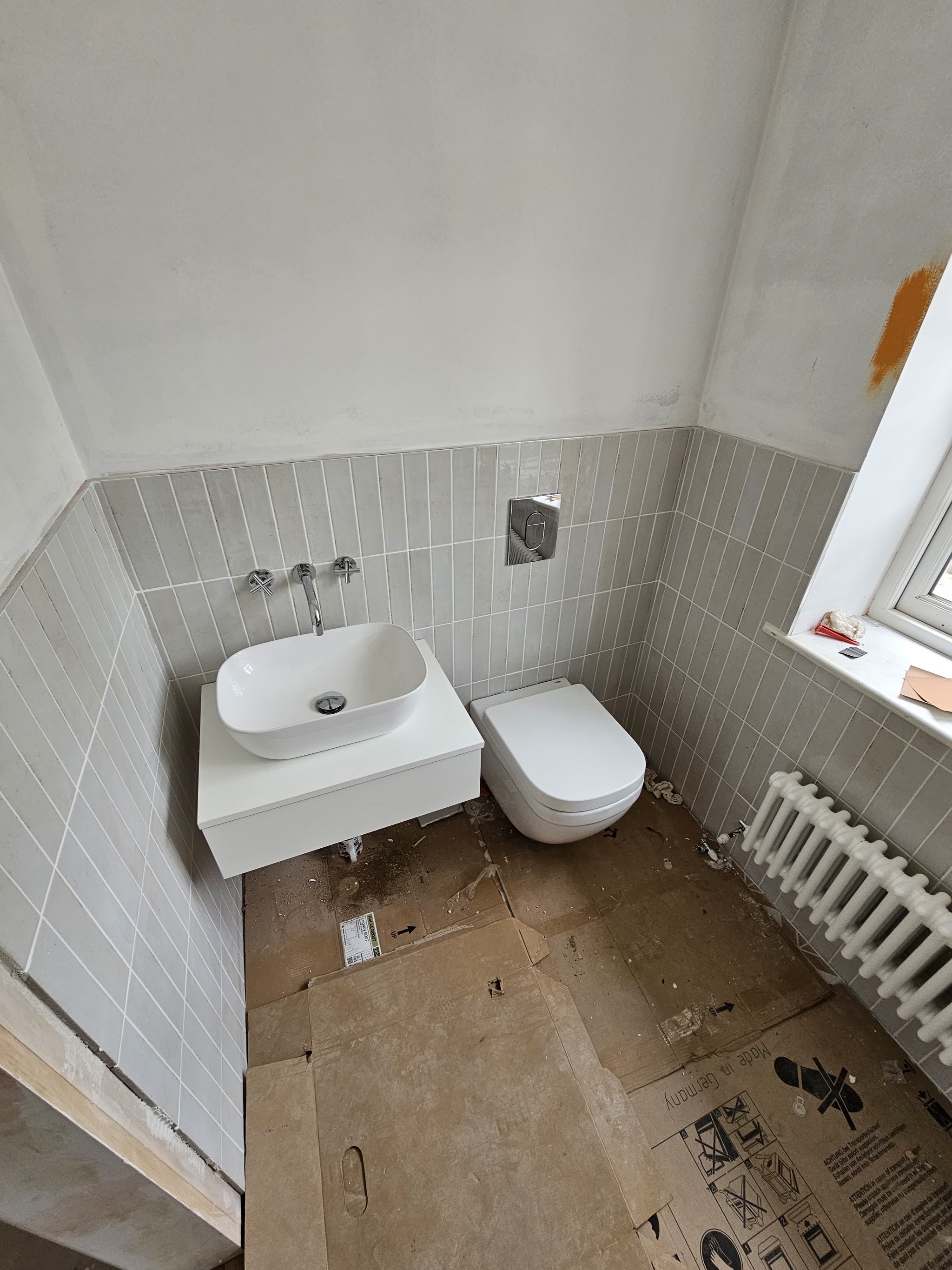 Bathroom with sage vertical wall tiles, a wall-hung toilet and a vanity basin